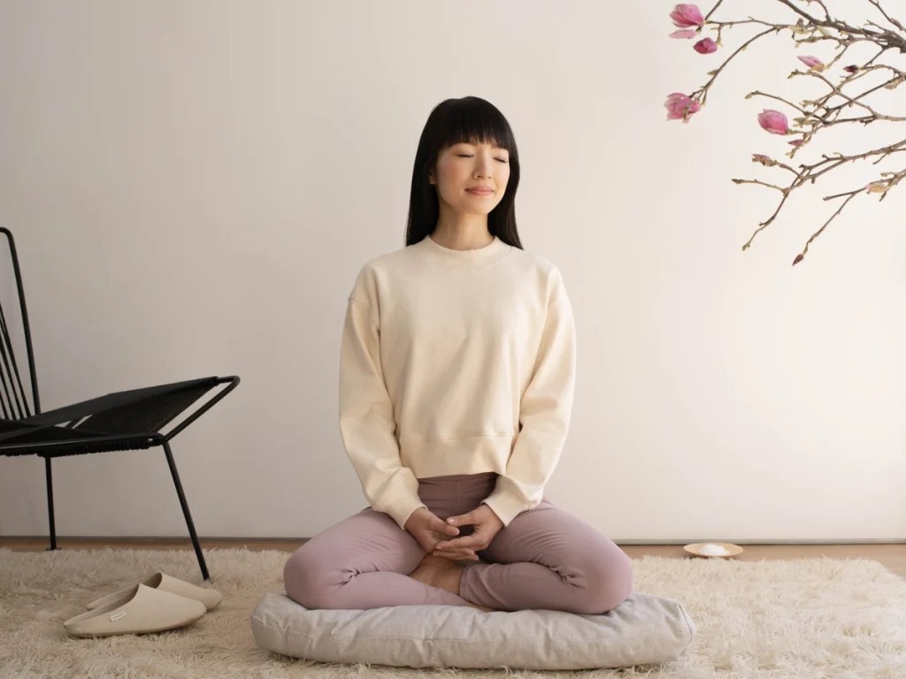 Marie Kondo meditating in a minimalistic, well-organized room